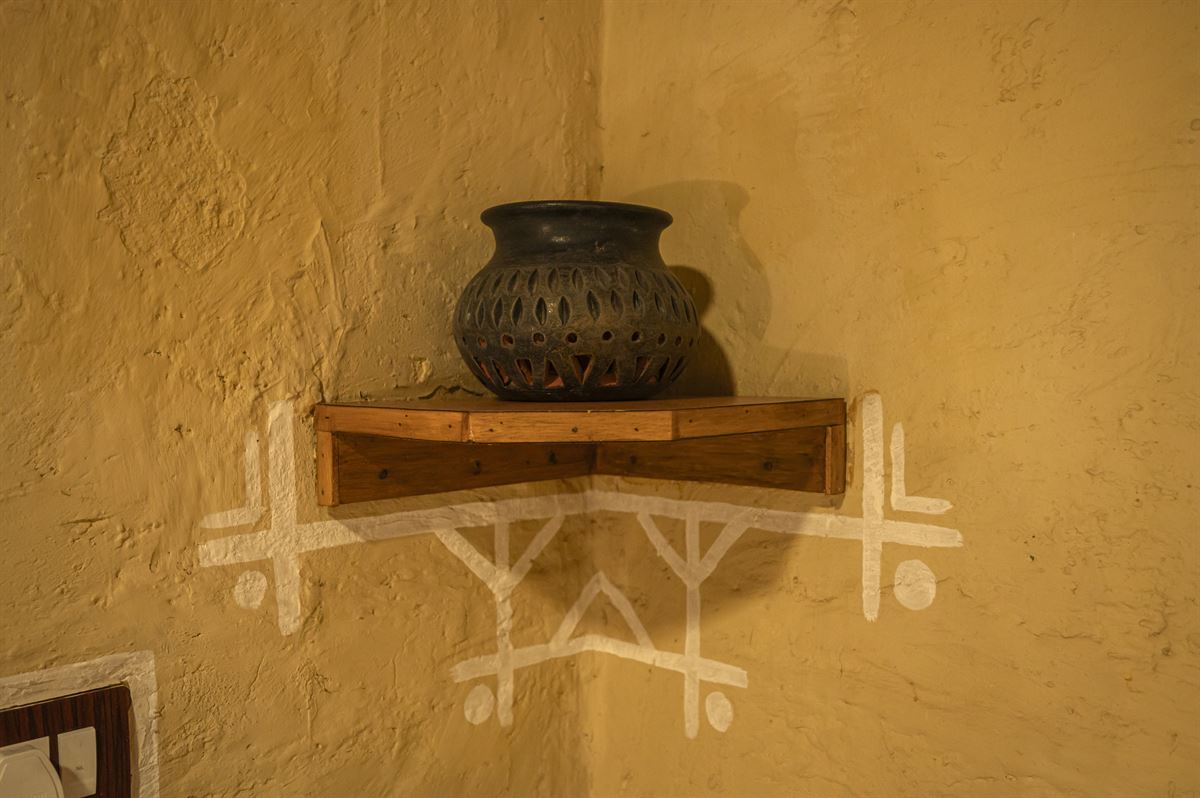 Traditional clay pot and hand-painted wall art detail at Shri Nilayam Kutir